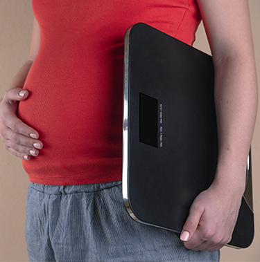 Femme enceinte portant une balance prise en plan serré