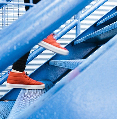 jambes avec des chaussures de sport rouge montant un escalier
